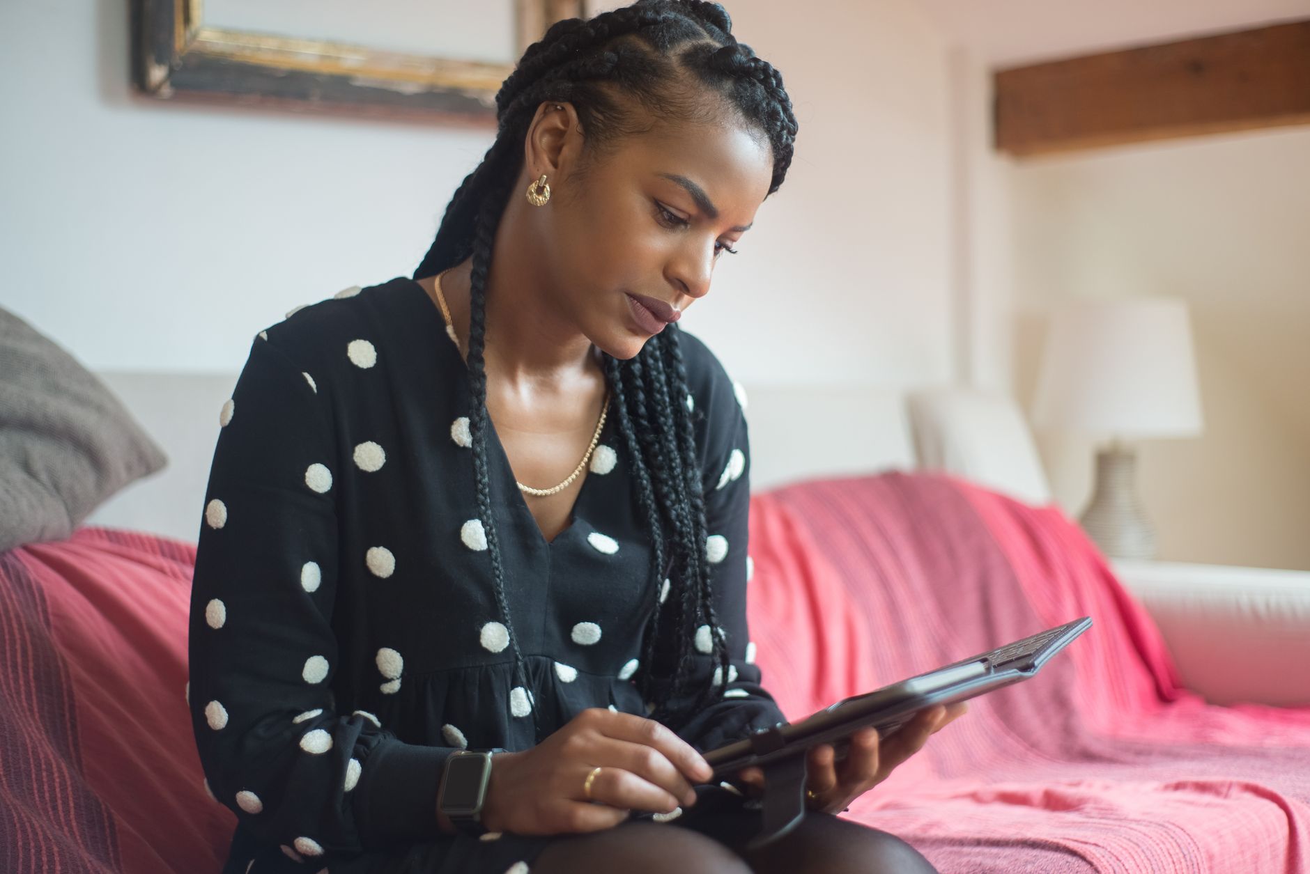 Femme utilisant une tablette sur un canapé confortable à la maison, en train de rédiger des légendes